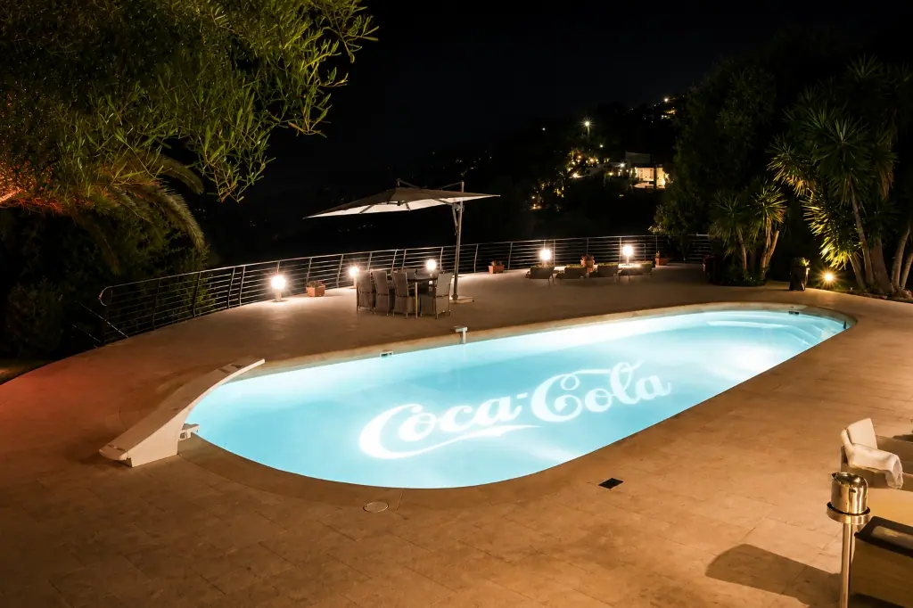 Logo beamed into pool water and architectural brand projection